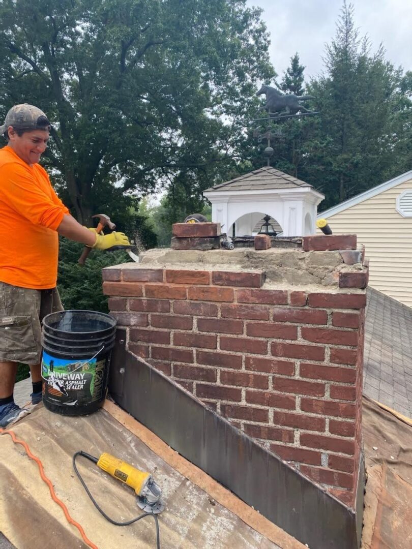 A man on the roof of a house working on a chimney.