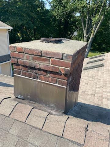 A brick chimney with a metal cover on it.